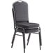 A stack of Lancaster Table & Seating black fabric banquet chairs with a cushion on the seat and back.