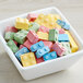A bowl filled with Candy Blox on a colorful surface.