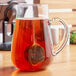 A glass pitcher of tea with a Choice stainless steel tea ball infuser in it.