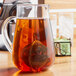 A glass pitcher with a Choice stainless steel tea strainer in it filled with tea.