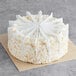 A David's Cookies coconut cake with white frosting and white strips on top.