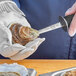 A person using a Schraf Boston Style Oyster Knife to open an oyster.