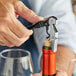 A hand with a black Acopa Waiter's Corkscrew opening a bottle of wine.