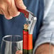 A person opening a wine bottle with an Acopa waiter's corkscrew.