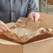 A person opening a box with Lavex natural kraft brown packing paper.