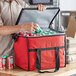 A man putting cans into a red Choice insulated cooler bag.