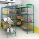 A Regency green wire shelving unit in a grocery store aisle filled with food.