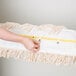 A hand holding a white mop pad with a yellow ruler