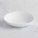 A white GET Enterprises Riverstone melamine serving bowl on a marble surface.
