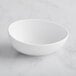 A white GET Enterprises Riverstone melamine bowl on a marble surface.