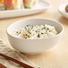 A white GET Enterprises Riverstone melamine bowl filled with rice and black sesame seeds.