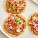 A group of tortillas with Goya refried pinto beans and vegetables on top.