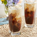 Two glasses of iced coffee with brown liquid made with Goya Coconut Milk, ice, and flowers.
