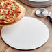 A 14" white corrugated pizza circle on a table with a pizza.