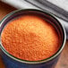 A bowl of powdered orange Goya Sazon seasoning.