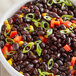 A bowl of Goya black beans with green peppers and onions.