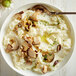 A bowl of Idahoan Creamy Classic mashed potatoes with mushrooms and a spoon.