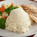 A plate of Idahoan Smartmash mashed potatoes with broccoli and chicken.