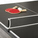 A red ping pong paddle and white ball on an Atomic Hampton table.
