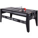 A Triumph 4-in-1 game table set up for table tennis with paddles and a ball.