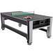 A Triumph 3-in-1 Swivel Game Table with a black and silver ping pong top set up with rackets and balls.