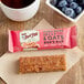 A close up of a Bob's Red Mill Peanut Butter Jelly & Oats Bar next to a cup of coffee.