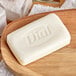 A white bar of Dial soap on a wooden surface.