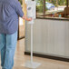 A man standing in front of a Dial Professional touch-free hand sanitizer dispenser on a stand.