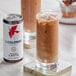 A glass of iced mocha latte with a can of La Colombe Mocha on the table.
