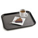A black non-skid Cambro tray with a piece of cake and a cup of coffee.
