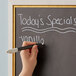 A hand writing on a chalkboard with a white chalk marker.