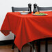 An orange Intedge rectangular table cover on a table with a plate of food.