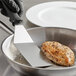 An OXO Good Grips turner on a pan with a piece of meat.