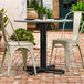 A Lancaster Table & Seating Excalibur black table base with FLAT Tech levelers on a brick patio.