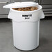 A white Rubbermaid BRUTE ingredient storage bin with a lid full of potatoes.