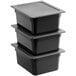A stack of three Vigor black plastic food pans with secure sealing covers.