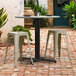 A Lancaster Table and Seating outdoor table with stools on a brick patio.