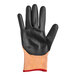 A pair of black and orange Mercer Culinary food processing gloves with a red stripe.