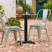 A black Lancaster Table & Seating outdoor table base on a brick patio.