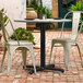 A Lancaster Table & Seating black table base with table and chairs on a brick patio.