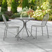 A Lancaster Table & Seating Harbor Gray outdoor patio table with two chairs on a patio.