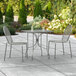 A Lancaster Table & Seating Harbor Gray rectangular outdoor table with two chairs on a patio.