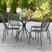 A black Lancaster Table & Seating table and chairs on a patio.