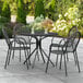 A Lancaster Table & Seating Harbor black outdoor table with chairs on a patio.