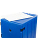 A navy blue Cambro mobile cart with a white sheet over a blue plastic container.
