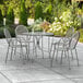 A Lancaster Table & Seating Harbor Gray outdoor patio table with ornate legs and four arm chairs.