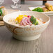 A bowl of rice with broccoli and other vegetables in a Thunder Group gold orchid melamine bowl.