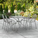 A Lancaster Table & Seating rectangular outdoor table with chairs on a patio.