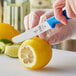 A person using a Mercer blue rounded tip paring knife to cut a lemon.