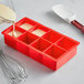 A red Choice silicone ice mold being filled with a white substance.